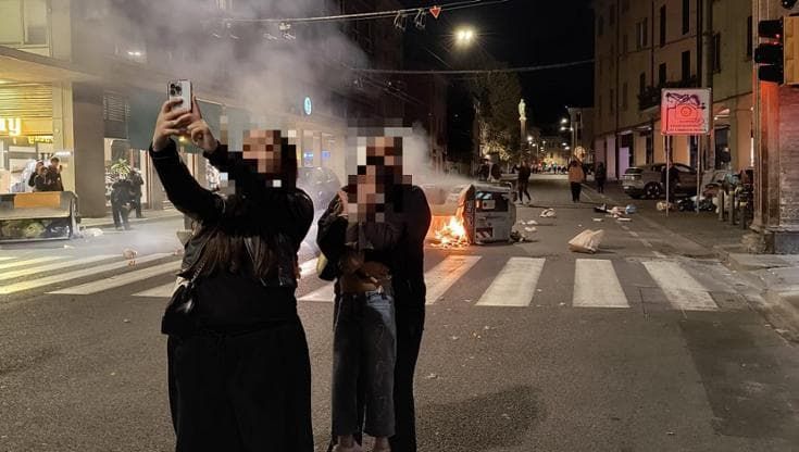 Il selfie davanti ai cassonetti che bruciano nella notte degli scontri a Bologna