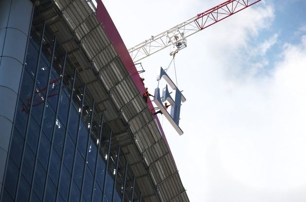 Milano: "riggers" al lavoro per installare la maxi-insegna sul tetto del grattacielo
