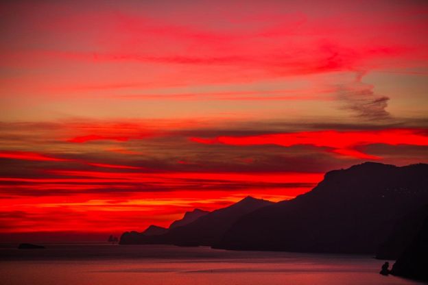 Positano, il cielo è rosso fuoco: il tramonto come una gouache