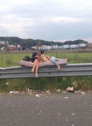Due prostitute sul ciglio della strada sdraiate sopra un materasso sul guardrail
