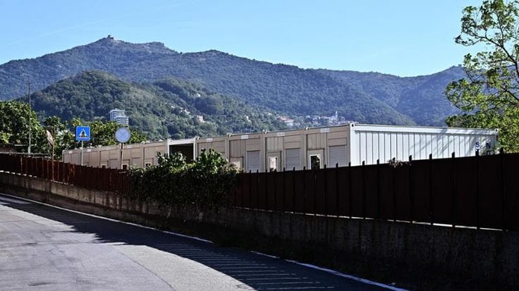 Genova, migranti minori nei container su un’area di proprietà di una consulente dell’assessora. La collaboratrice si dimette. Bucci: “C’è stato un inciampo, i profughi non andranno più lì”. Lite tra il sindaco e Bertorello (Lega)
