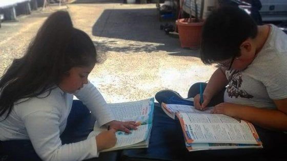Milano, i fratellini rom fanno i compiti fuori dalla roulotte: niente lezioni online, ma penna e quaderno
